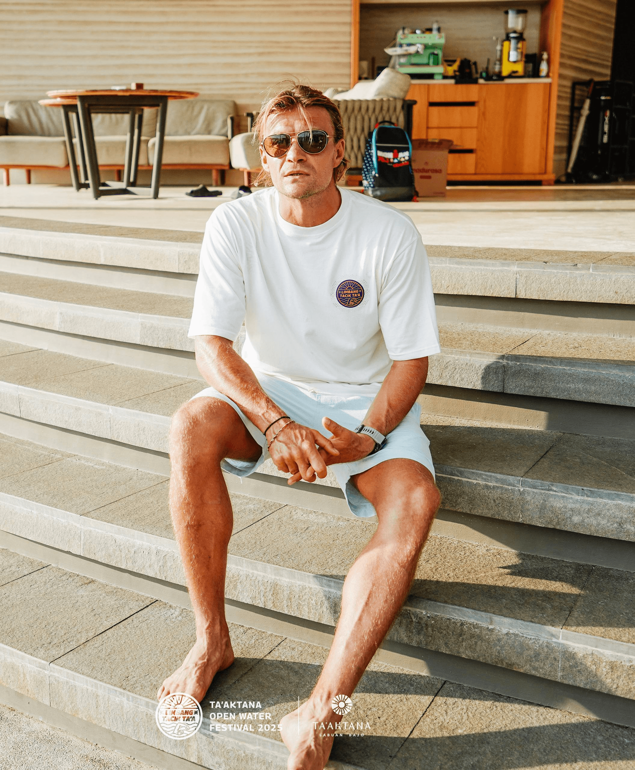 Alexander Taraskin seated on steps in a white shirt and sunglasses