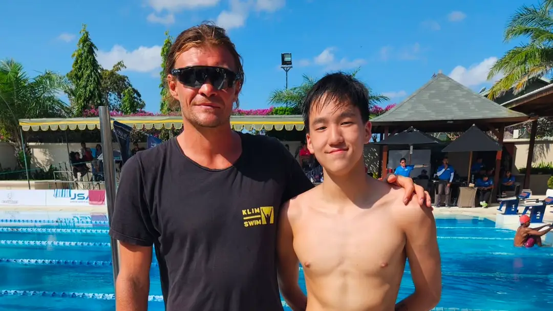 A coach and swimmer beside the pool at a previous Bali camp
